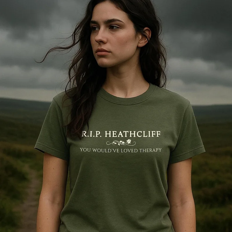 An olive green short-sleeved t-shirt featuring the white text R.I.P. HEATHCLIFF, a small decorative floral flourish, and the text YOU WOULD'VE LOVED THERAPY printed across the chest in a clean, sans-serif font style.