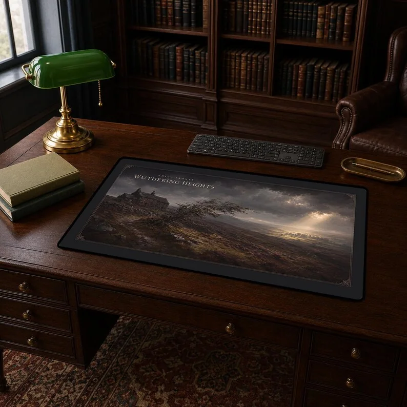 Emily Brontë’s Wuthering Heights desk mat showing the Heights on the wild moors, Thrushcross Grange in distant sunlight and a windswept tree.
