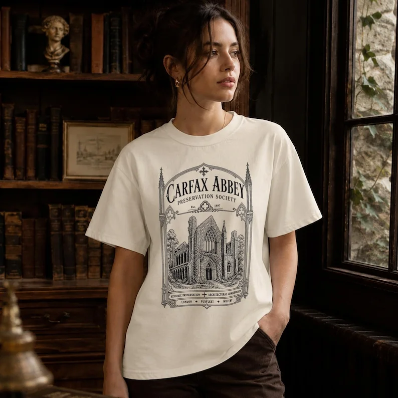 Woman wearing an ivory Carfax Abbey literary T-shirt featuring Gothic architecture inspired by Dracula.