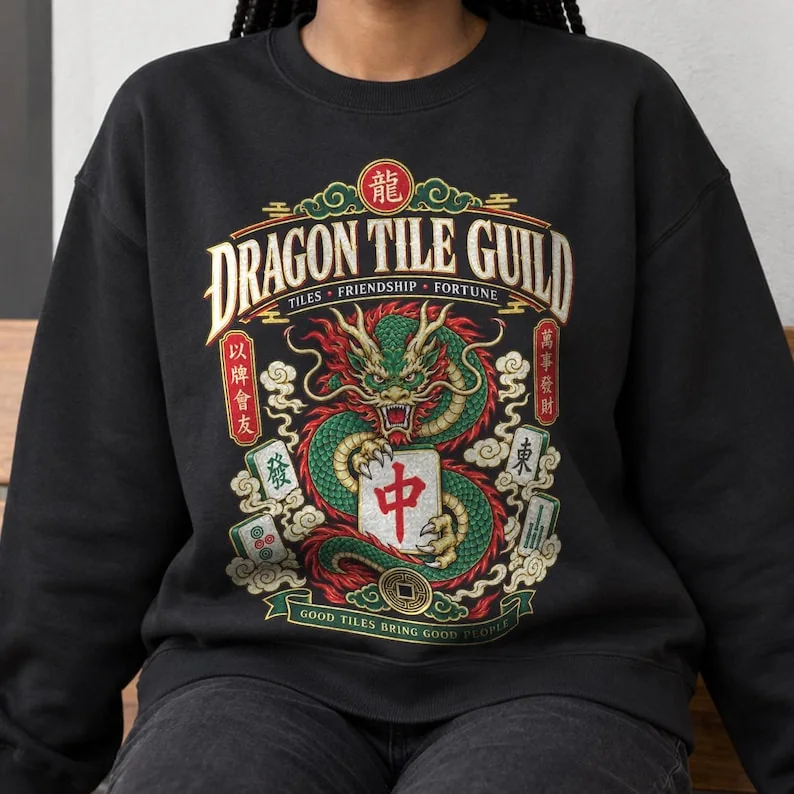 Woman wearing black Dragon Tile Guild mahjong sweatshirt with green dragon, red and gold crest and mahjong tile artwork.