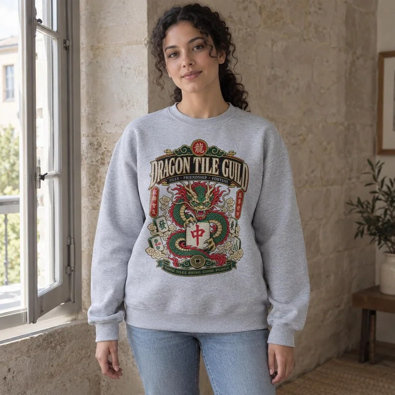 Woman wearing Sport Grey Dragon Tile Guild mahjong crewneck with red, green and gold dragon artwork.