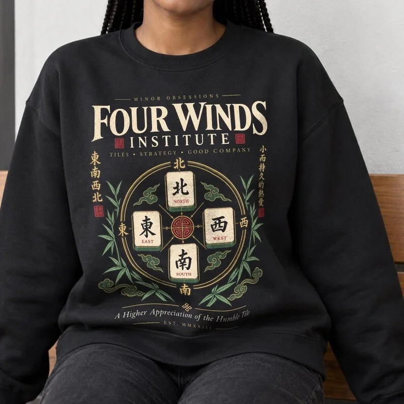 Woman wearing black Four Winds Institute mahjong sweatshirt featuring North, South, East and West wind tiles with bamboo artwork.