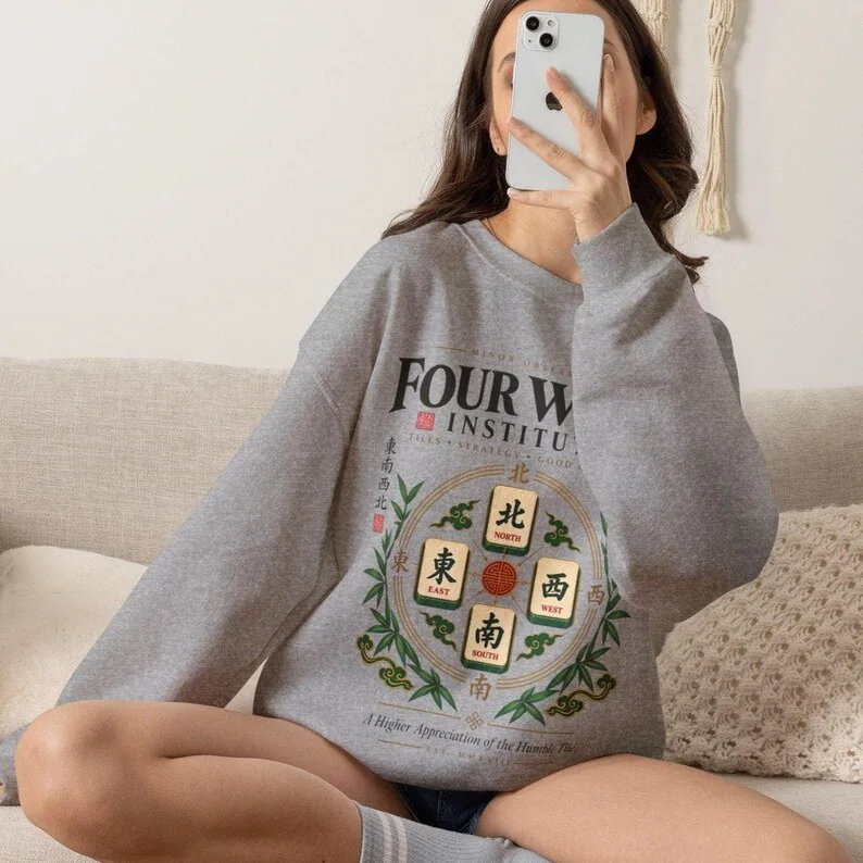 Woman wearing Sport Grey Four Winds Institute mahjong sweatshirt with four wind tiles, bamboo and vintage green and gold artwork.