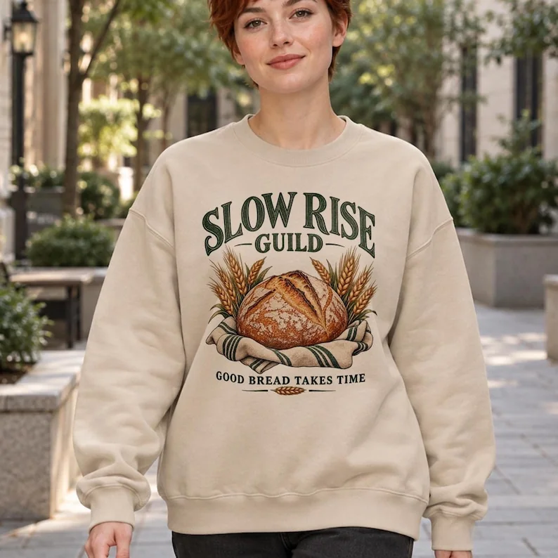 Slow Rise Guild sourdough sweatshirt in sand, shown on woman outdoors with vintage bread and wheat graphic